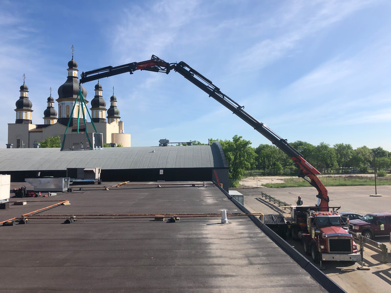 Crane lifts air unit onto roof.